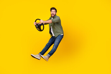 Full size photo of nice young man jump hold wheel wear shirt isolated on yellow color background