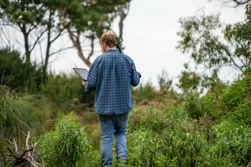 regenerative organic farmer, taking soil samples and looking at plant growth in a farm. practicing sustainable agriculture.