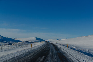 Remote farm in snow-covered valley under blue sky