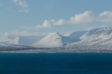 Snowy mountains with serene blue sea in foreground