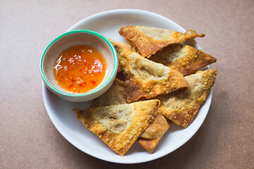 Closeup fried wontons with chili sauce on white plate