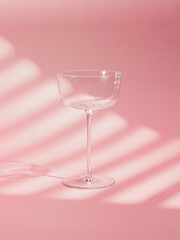 An elegant image of an empty glass goblet on a vibrant pink background. The minimalist composition highlights simplicity and sophistication, ideal for drink themes, style and modern design.
