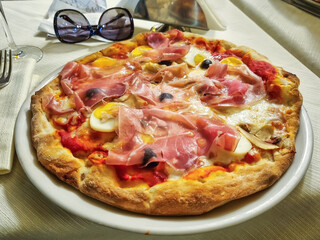 Delicious traditional Italian Prosciutto funghi pizza simply served in a small trattoria in Trastevere, Rome, Italy