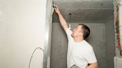 Worker is putting a gypsum plaster on a wall using a spatula. 