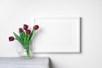 Blank landscape artwork frame mockup with flowers over white wall, copy space for art design