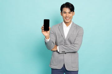 Young smiling Asian businessman holding and showing blank screen mobile phone application isolated on green background, Asian Thai model