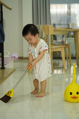Asian young boy in white clothes sweeping with fantacy yellow broom set and home vibe background