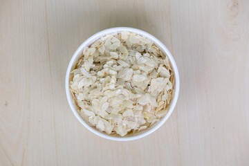 Flattened rice or Chira on a white bowl on a wooden background. Top view.