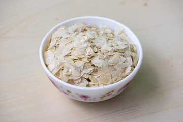 Flattened rice or Chira on a white bowl on a wooden surface.