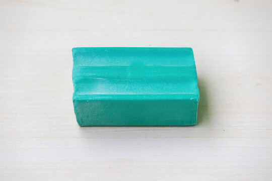 A green dishwash soap bar on a light wooden surface. Top view.
