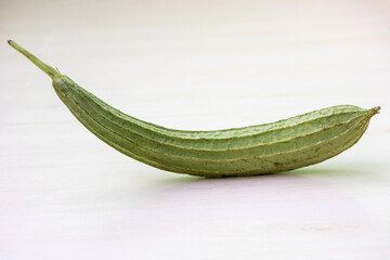 Angled luffa gourd on wooden surface