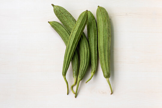 Fresh Chinese okra or ridge gourds on wooden surface. It is also known as Silk squash, Jhinga, and Turai. Top view.