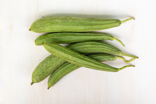 Fresh ridge gourds on wooden surface. It is also known as Chinese okra, Silk squash, Jhinga, and Turai. Top view.