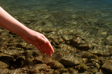 Happy. People in nature. A woman touches the water. A woman's hand on the surface of water, river, sea, ocean.