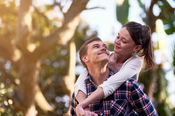 Fototapeta premium Piggyback, couple or happy people outdoor for date, love and connection in nature together. Smile, man and woman on fun adventure to park for relationship, bonding and playing outside on weekend