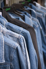 Closeup of blue jeans jackets on hangers in the fashion store showroom in the street