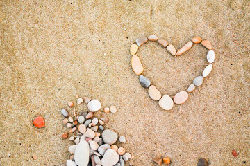 A heart made of rocks is on a sandy beach. The rocks are scattered around the heart, creating a beautiful and unique design. Concept of peace and tranquility, as the heart