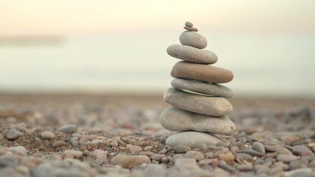 A stack of rocks on a beach. The rocks are arranged in a pyramid shape. The scene is peaceful and serene, with the ocean in the background. The rocks seem to be a symbol of stability and strength