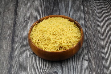 White gluten free vermicelli made from rice flour. Italian pasta in wooden spoon on dark textured background. Top view, space for text.