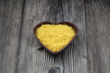 White gluten free vermicelli made from rice flour. Italian pasta in wooden spoon on dark textured background. Top view, space for text.