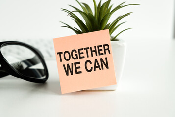 Together We Can text on adhesive note stick on a flower pot on white background.