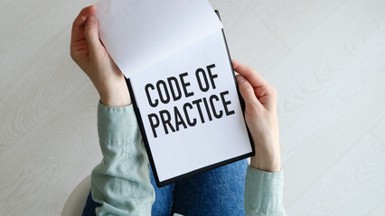 Closeup on business woman holding a card with CODE OF PRACTICE message, business concept image with soft focus background.