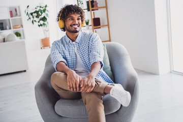 Photo of handsome cheerful guy dressed plaid shirt enjoying music headphones indoors room home house