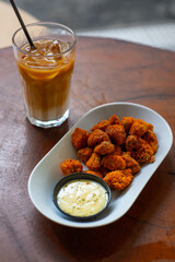 deep fried crispy breaded mushroom on elongated white plate, served with creamy dipping sauce, on...