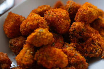 deep fried crispy breaded mushroom on elongated white plate, served with creamy dipping sauce, on wooden table