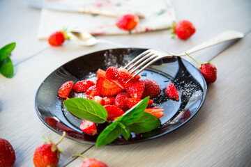 fresh fruit salad of ripe strawberries on a light wooden table