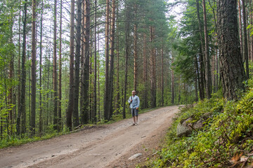 a male tourist in shorts and a backpack walks along a forest road on a hot summer day, tourism and...