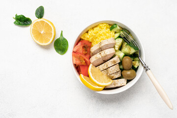 Healthy salad with chicken, tomato, cucumber, olives and rice in bowl on white background with copy space