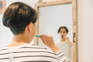 A teenage girl is brushing her teeth in front of a mirror, concept of personal hygiene and self-care