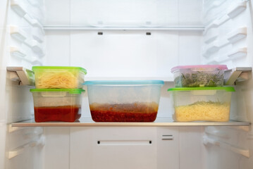Leftovers in containers on a shelf in the refrigerator.