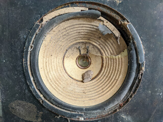 The once powerful woofer now shows signs of wear and damage, its surface is marred by cracks and dents. Resonant bass reflects a history of intense use.