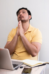 Young man praying for solution to the school and the homework front his laptop