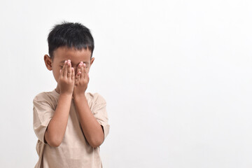 Image of Asian child posing with both hands covering his head on a white background. portrait of an Asian boy