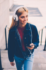 Positive young woman with blonde hair listening audio lesson with learning foreign languages in...