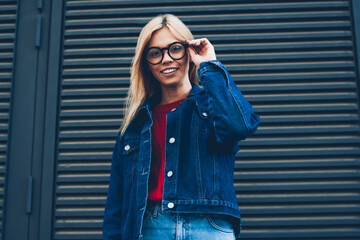 Half length portrait of charming positive young woman with spectacles dressed in stylish denim...