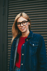 Half length portrait of happy stylish young woman with blonde hair smiling at camera while posing...