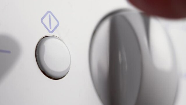 Pressing the button of the home kitchen appliance for washing dishes in closeup. Electricity saving and energy efficiency concept. Turning on the dishwasher