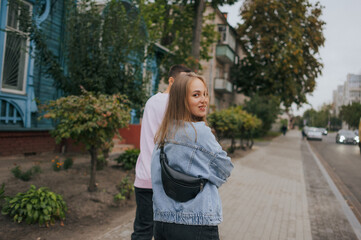 A happy young couple in love, a boy and a girl, on a walk in the city, hugging and walking. Urban European love story and photo shoot