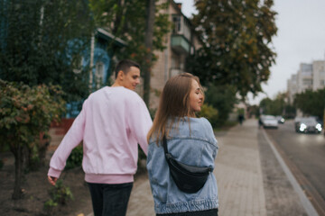 Obraz premium A happy young couple in love, a boy and a girl, on a walk in the city, hugging and walking. Urban European love story and photo shoot