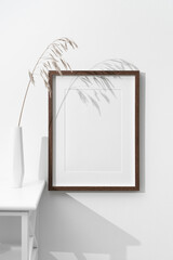 Blank portrait art frame mockup on white wall with botanical decor, copy space