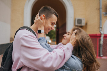 A happy young couple in love, a boy and a girl, on a walk in the city, hugging and walking. Urban European love story and photo shoot