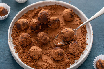 Artisanal chocolate truffles dusted with cocoa powder on a plate with a spoon