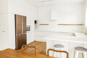 Modern kitchen interior. Stylish white kitchen cabinets with brass knobs, granite island and appliances in new scandinavian house. Modern minimal kitchen design