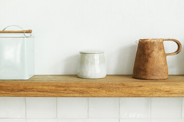 Wooden shelf with utensils, cups and decor on rustic wall background in modern kitchen in new...