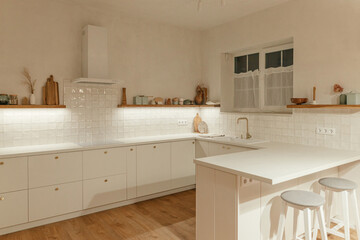 Modern kitchen interior. Stylish white kitchen cabinets with brass knobs, granite island, appliances and light in new scandinavian house. Modern minimal kitchen design