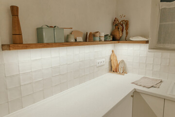 Modern minimal kitchen design. Stylish white kitchen cabinets with brass knobs, wooden shelves with...